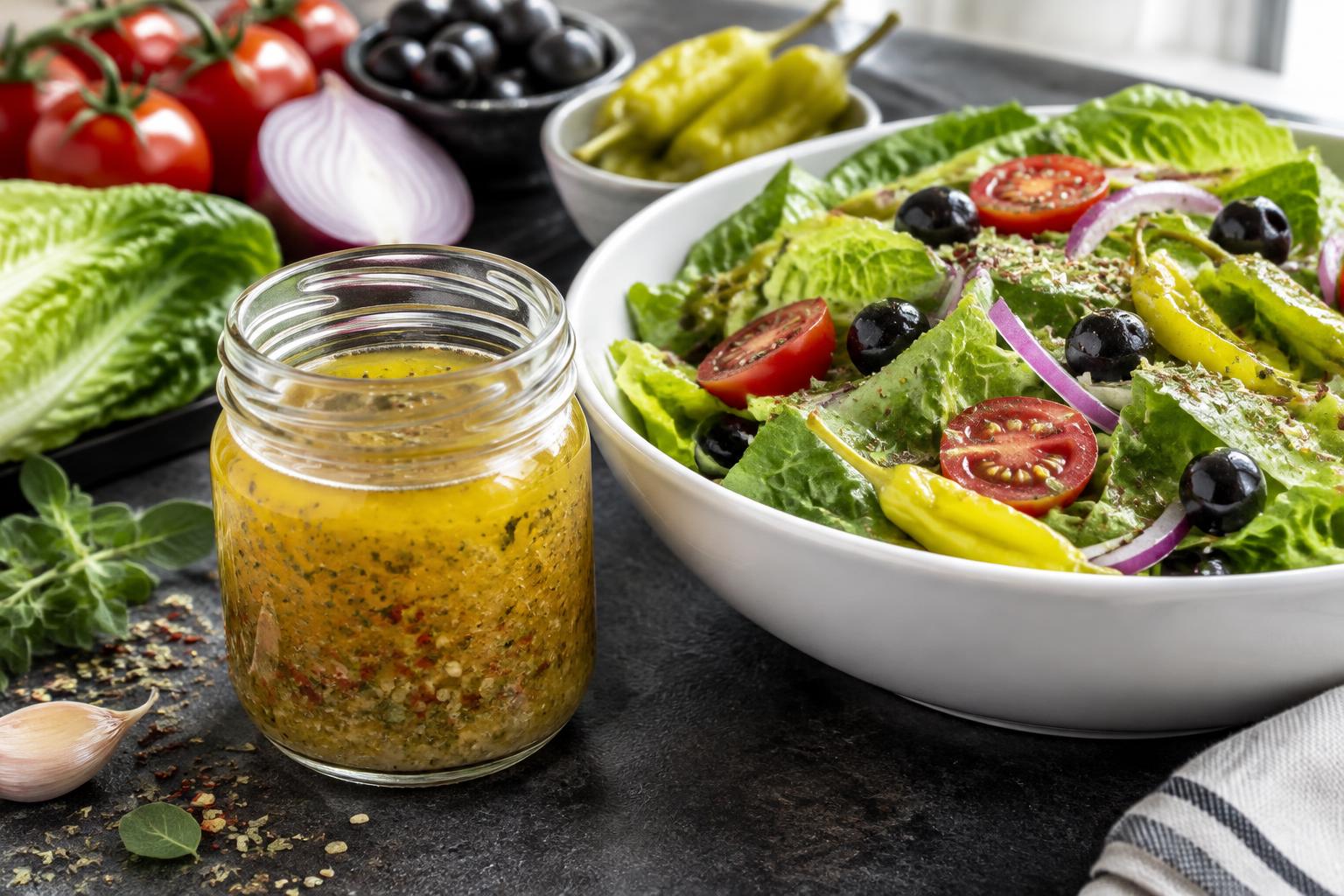 Illustrative herb vinaigrette in a glass jar beside a green salad